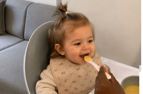 Baby krijgt een hapje fruit in de kinderstoel
