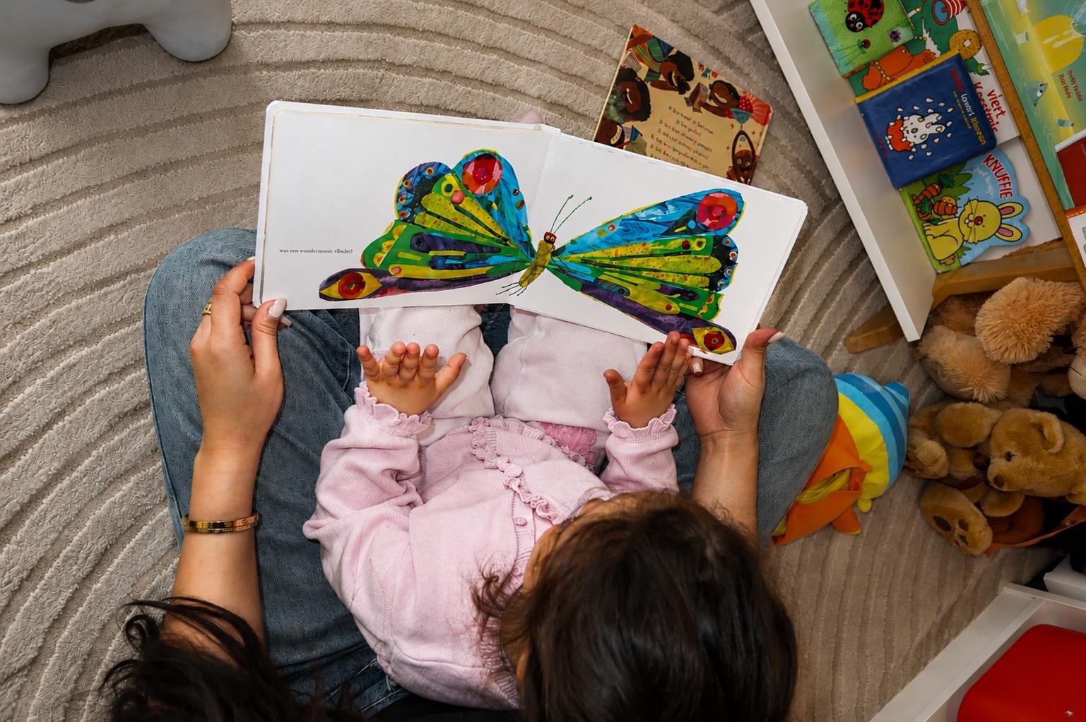 Kind en medewerker lezen samen een boek met een vlinder