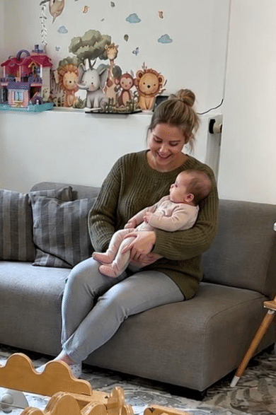 Medewerker houdt een baby vast op de bank in de groepsruimte